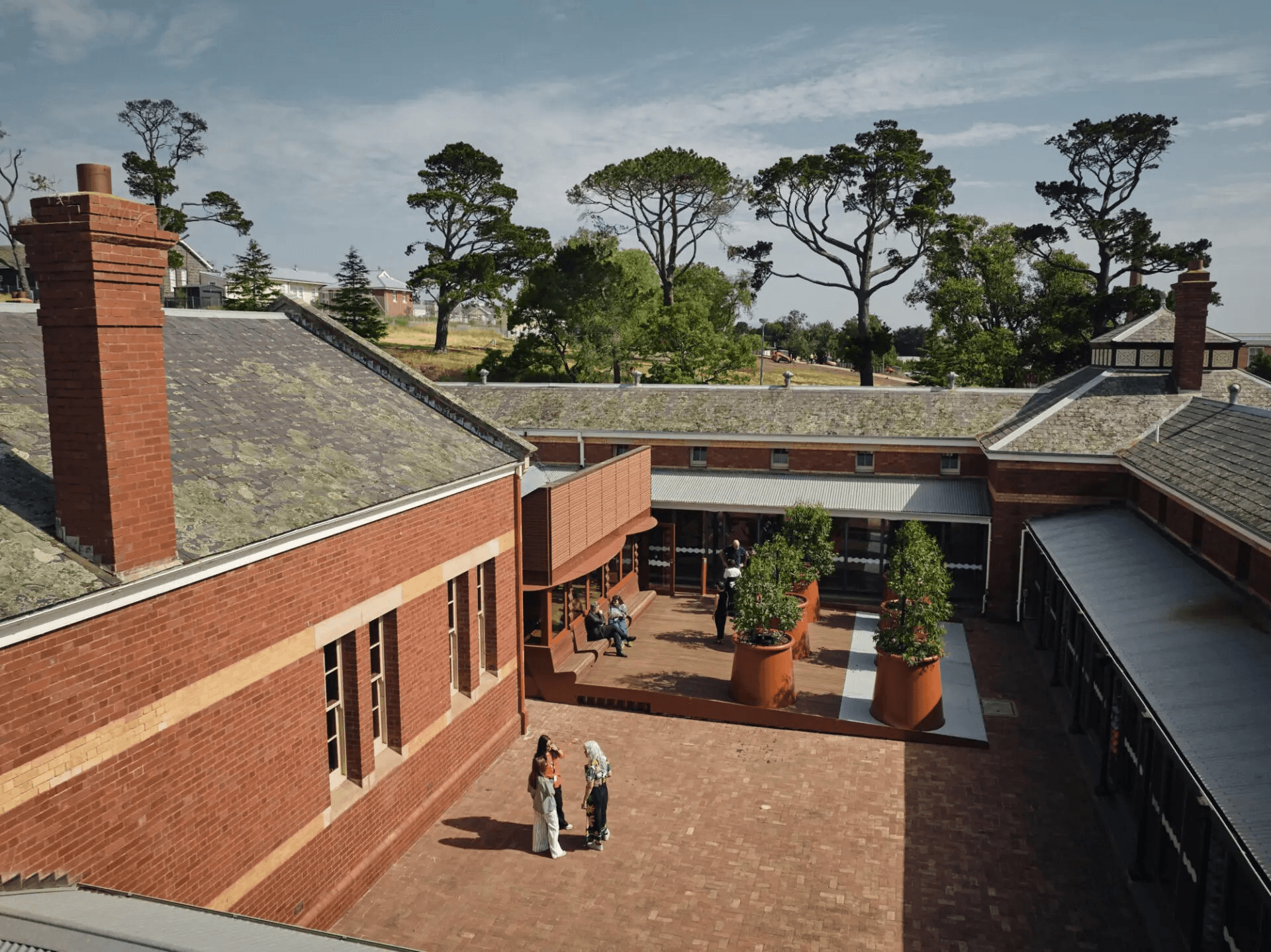 Birdseye view of courtyard. Red brick buildings and potted trees.